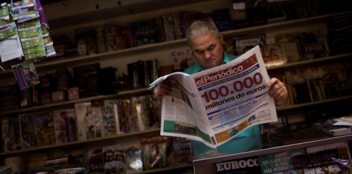A man reads a newspaper announcing a bailout of up to euro 100 billion ($125 billion) to rescue failing banks, in a bookstore in Barcelona, Spain (AP Photo/Emilio Morenatti).