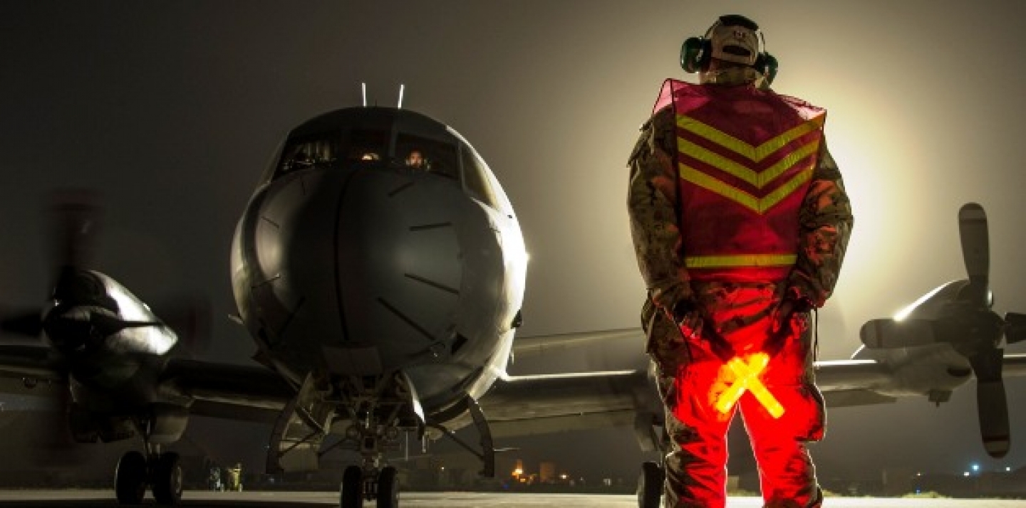 A Royal Canadian Air Force technician guides a CP-140 Aurora to its parking area during Operation IMPACT in Kuwait on February 5, 2015. (Canadian Forces Combat Camera, DND)