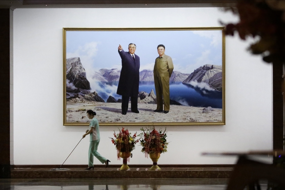 A hotel staff member mops the floor below a portrait of the late North Korean leaders Kim Il Sung, left, and Kim Jong Il on June 19, 2017, in Pyongyang, North Korea. (AP Photo/Wong Maye-E)