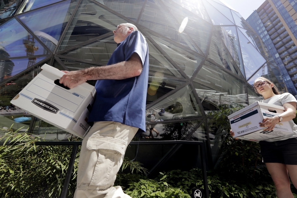 Outside of the Amazon headquarters in Seattle, volunteers carry boxes of petitions urging the tech giant to stop selling its face surveillance system, Rekognition, to the government. (AP Photo/Elaine Thompson)