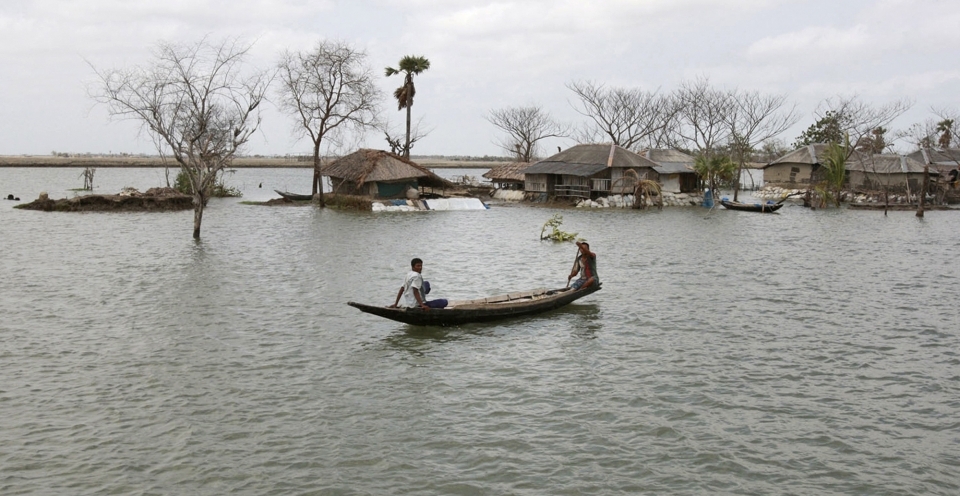 In this 2010 photo, a villager rows a boat past the Gabura village, an area affected by last year's cyclone Aila in Satkhira, about 175 kilometres from Dhaka, Bangladesh. (AP Photo/Pavel Rahman)