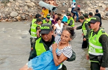 Elderly refugee carried by Colombian National Police across the river from Venezuela into Colombia/Wikimedia Commons