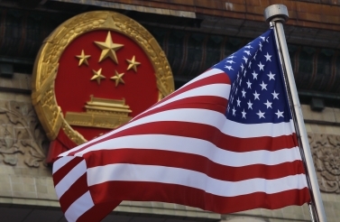 An American flag is flown next to the Chinese national emblem in Beijing (AP Photo/Andy Wong)