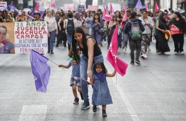 A little girl holds a flag walking in front of protestors during a protest in Mexico City on February 2, 2019. (AP Photo/Anthony Vazquez)