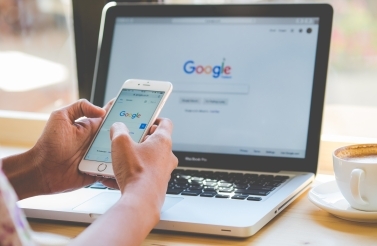 A woman is typing on Google search engine from a laptop and smart phone. (Shutterstock)