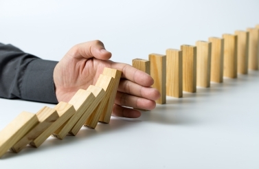 Hand stopping falling dominoes