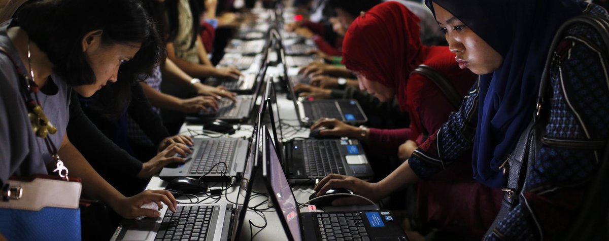 Indonesian women fill out job application forms on laptops in Jakarta on August 22, 2014. (Reuters/Beawiharta)