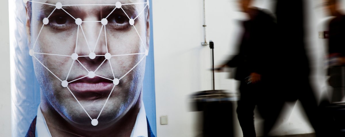 People walk past a poster simulating facial recognition software at the Security China 2018 exhibition on public safety and security in Beijing, October 24, 2018. (Thomas Peter/REUTERS)