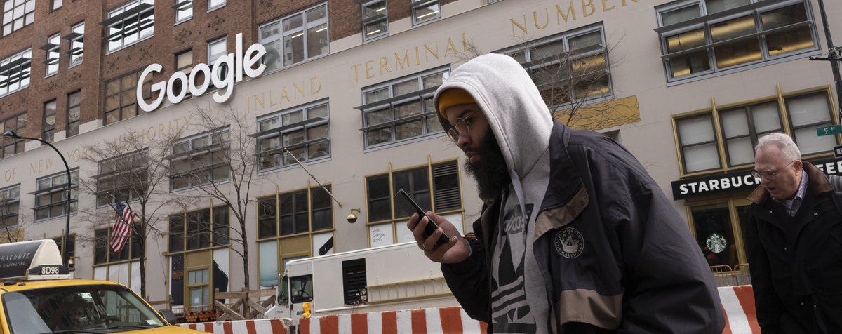 A man using a mobile phone walks past Google offices in New York. (AP Photo/Mark Lennihan)